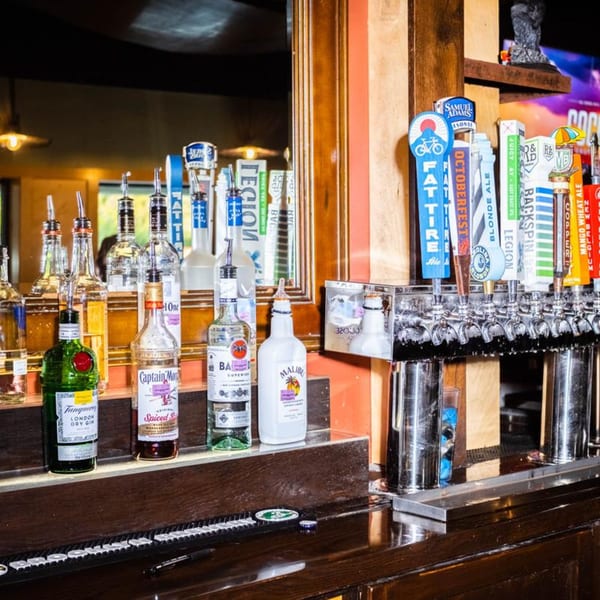 A well-stocked bar at The Rusty Onion with liquor bottles and multiple beer taps.