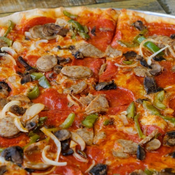 Close-up of a Rusty Onion pizza with pepperoni, sausage, mushrooms, green peppers, and onions.